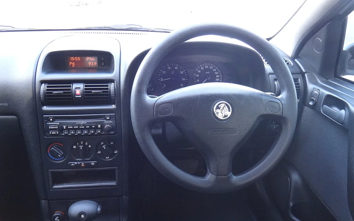 Detailer wiping car dashboard and air vents with a microfiber brush