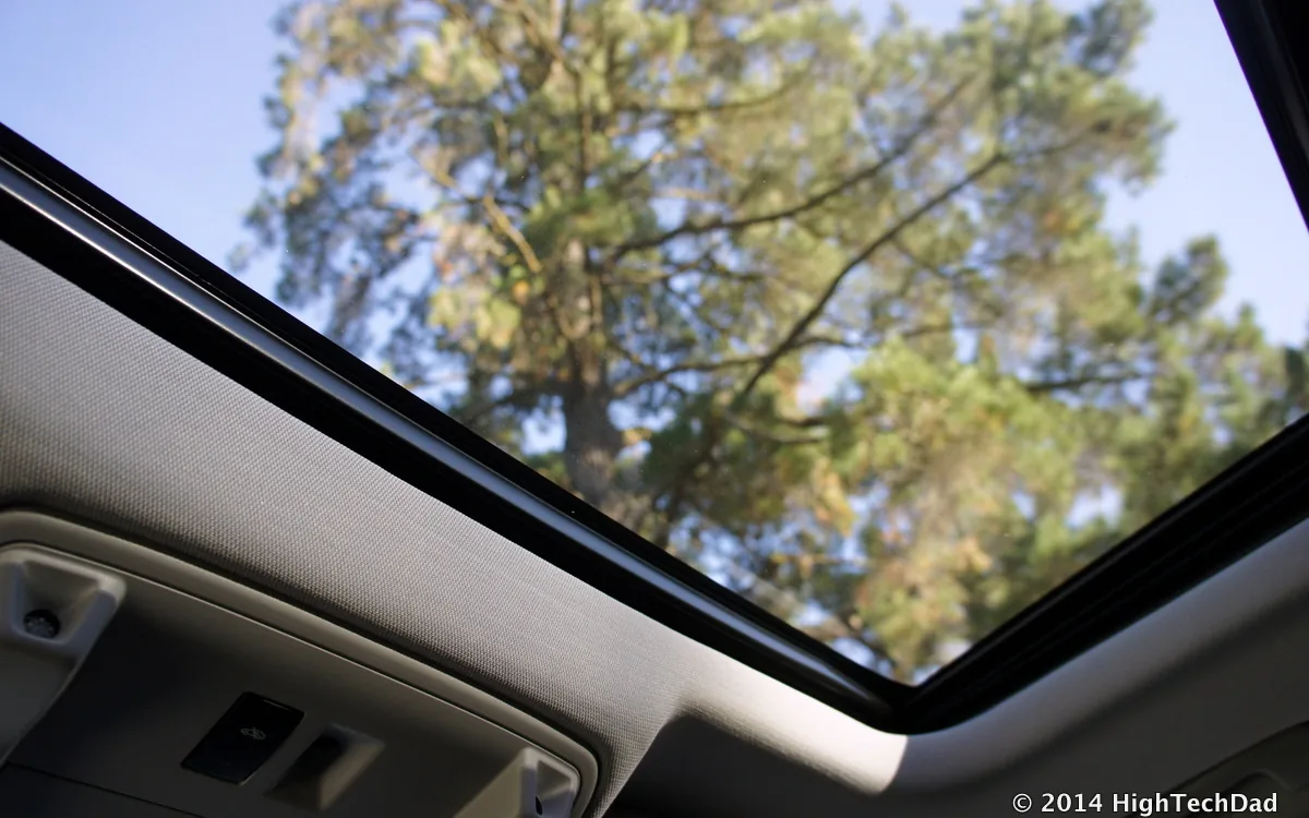 Car interior showing open panoramic sunroof with sky view