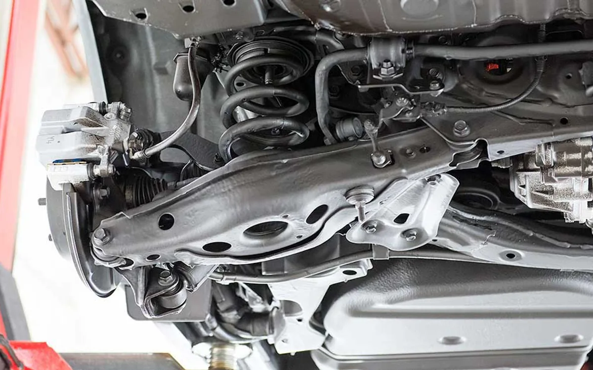 Anti-rust underbody coating being sprayed on a raised car chassis